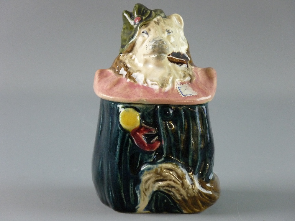 A CONTINENTAL MAJOLICA TOBACCO JAR in the form of a dog in costume with a pink ruff, 13 cms high,