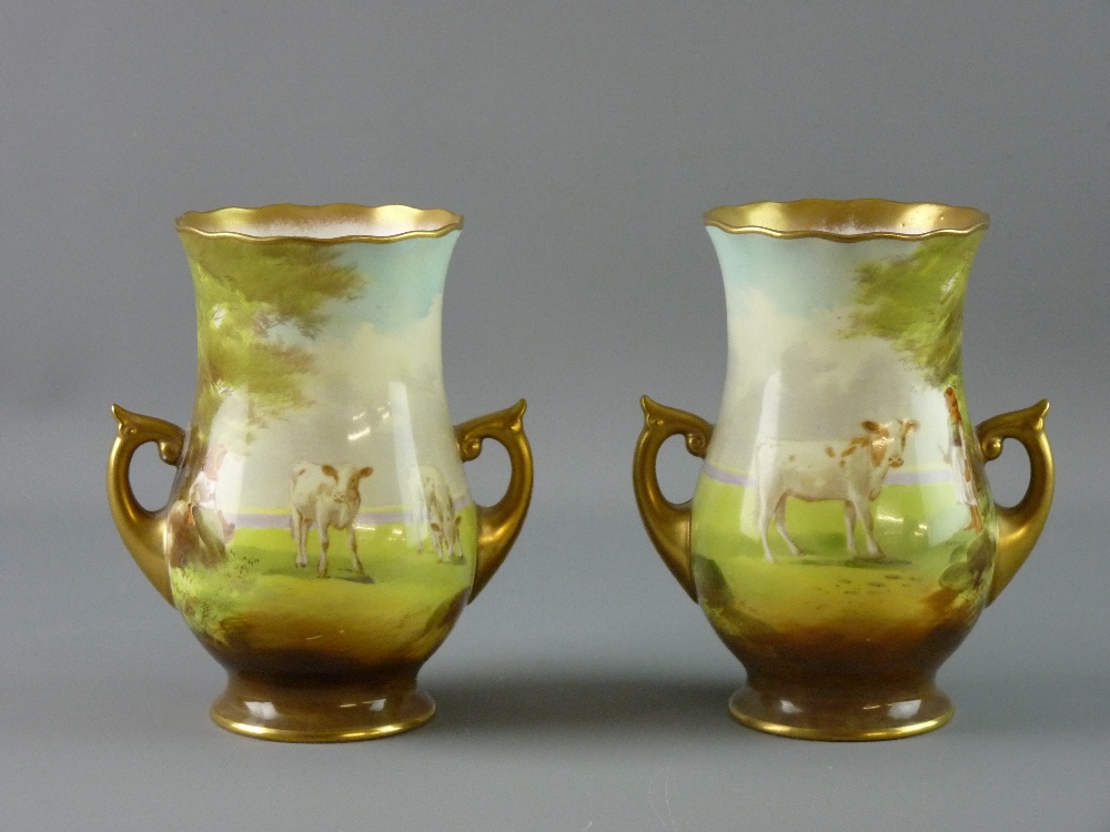 A PAIR OF ROYAL DOULTON VASES hand painted by J Hancock, with twin gilt handles and all over