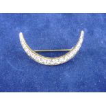 A YELLOW METAL CRESCENT BROOCH with a row of graduated czs