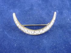 A YELLOW METAL CRESCENT BROOCH with a row of graduated czs