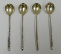 A SET OF FOUR RUSSIAN SILVER COFFEE SPOONS with spiral stems and floral engraved bowls with