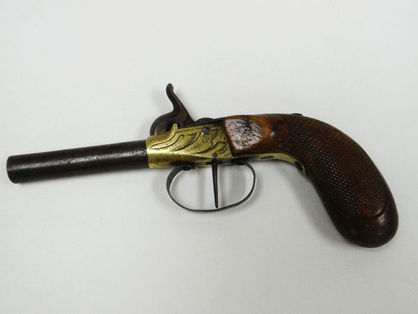 A NINETEENTH CENTURY PISTOL with foliate brass barrel and carved handle, 19cms long