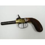 A NINETEENTH CENTURY PISTOL with foliate brass barrel and carved handle, 19cms long