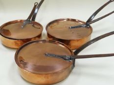 A SET OF THREE COPPER LIDDED SAUCEPANS each with long fitted iron handles to the lids and bodies and