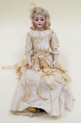 A VICTORIAN BISQUE HEAD DOLL of a young girl, having composition limbs and body and with closing and