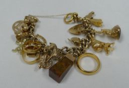 A GOLD CHARM BRACELET with approximately nineteen gold or part gold charms and including a 22ct gold