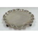 A SILVER SALVER having a wavy rim and raised on four scroll feet by Goldsmiths & Silver Smiths