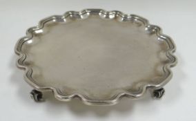 A SILVER SALVER having a wavy rim and raised on four scroll feet by Goldsmiths & Silver Smiths