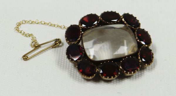 A VICTORIAN LOCKET with glass case surrounded by ten oval red stones