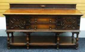 A WARING & GILLOWS OAK SIDEBOARD having a rail back and with raised cupboards and drawers above a