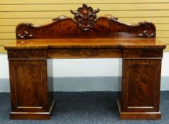 A VICTORIAN MAHOGANY PEDESTAL BREAKFRONT SIDEBOARD having a scrolling foliate rail back and a row of