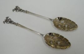 A PAIR OF SILVER BERRY SPOONS WITH ROMANESQUE TERMINALS having opposing serpents and winged finials,