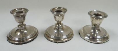 A TRIO OF SILVER CANDLE-HOLDERS with circular bases, 15ozs gross