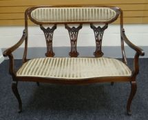 AN EDWARDIAN SETTEE in mahogany with upholstery to the seat and back and having three floral splats