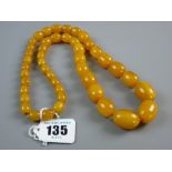A GRADUATED SET OF BUTTERSCOTCH AMBER BEADS, approximate measurements, 64 cms long, the largest bead