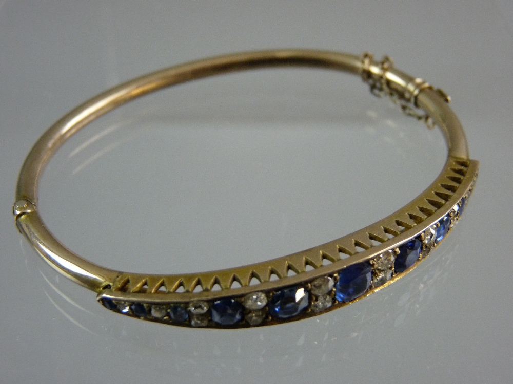 AN UNMARKED GOLD BRACELET having a graduated band of eleven sapphires (one of the smallest