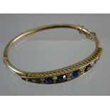 AN UNMARKED GOLD BRACELET having a graduated band of eleven sapphires (one of the smallest