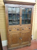 AN ANTIQUE OAK & PINE ONE PIECE WELSH CUPBOARD, the upper section having twin glazed doors with nine