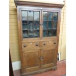 AN ANTIQUE OAK & PINE ONE PIECE WELSH CUPBOARD, the upper section having twin glazed doors with nine