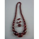 A DARK AMBER NECKLACE of graduated oblong beads and with four additional loose beads