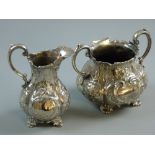AN ELECTROPLATED TWIN HANDLED SUGAR BASIN & CREAM JUG each with raised and scroll decoration and
