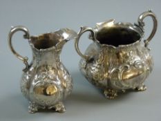 AN ELECTROPLATED TWIN HANDLED SUGAR BASIN & CREAM JUG each with raised and scroll decoration and