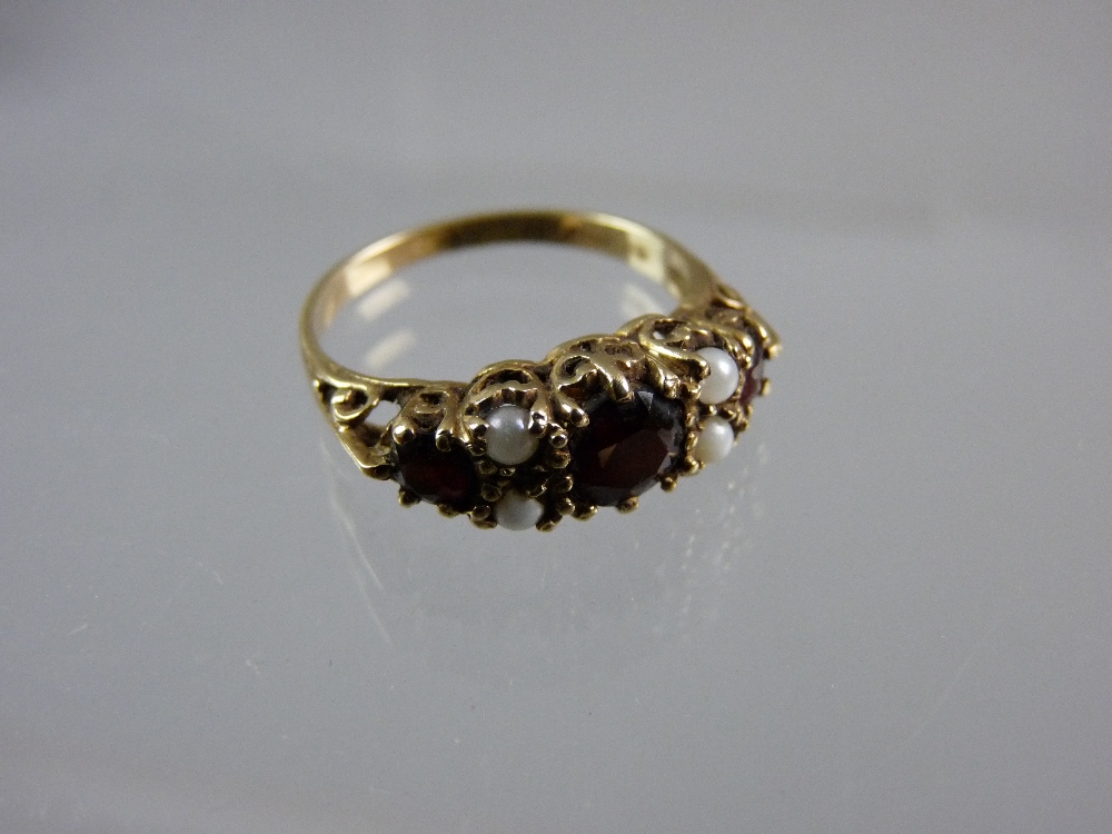 A NINE CARAT GOLD DRESS RING having a centre garnet with two small flanking opals and a smaller