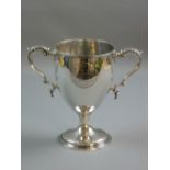 AN EARLY SILVER TROPHY CUP on a circular base with twin scrolled handles, inscribed to the front '