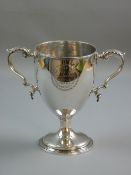 AN EARLY SILVER TROPHY CUP on a circular base with twin scrolled handles, inscribed to the front '