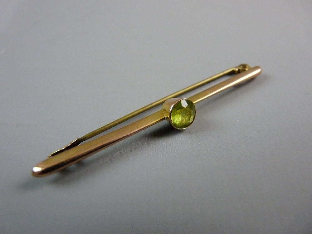 AN UNMARKED GOLD BAR BROOCH with single round cut peridot?, 2 grms gross