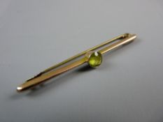 AN UNMARKED GOLD BAR BROOCH with single round cut peridot?, 2 grms gross