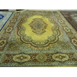 A MUSTARD GROUND KESHAN WOOL CARPET having a wide floral crimson and blue border and with a centre