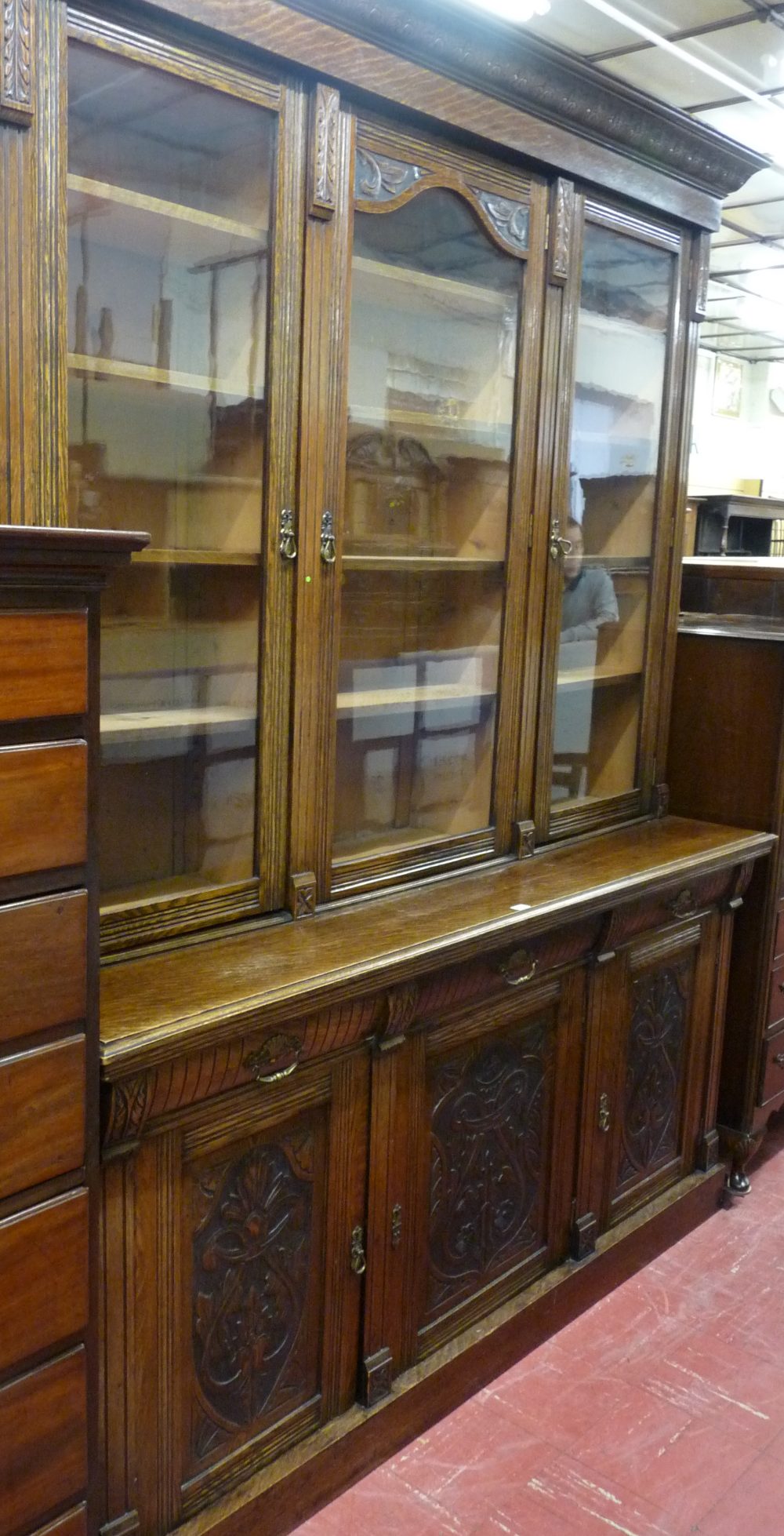 AN EARLY 20th CENTURY OAK AND PINE TWO PIECE BOOKCASE/CUPBOARD, the upper section having a leaf