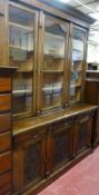 AN EARLY 20th CENTURY OAK AND PINE TWO PIECE BOOKCASE/CUPBOARD, the upper section having a leaf