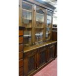 AN EARLY 20th CENTURY OAK AND PINE TWO PIECE BOOKCASE/CUPBOARD, the upper section having a leaf