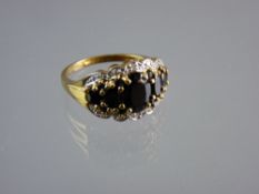 A NINE CARAT GOLD DRESS RING having a band of five graduated oval sapphires and tiny diamonds to the