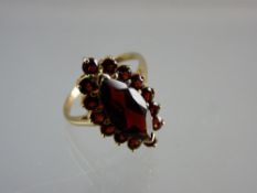 A NINE CARAT GOLD OVAL GARNET DRESS RING having a centre large oval garnet and tiny surrounding