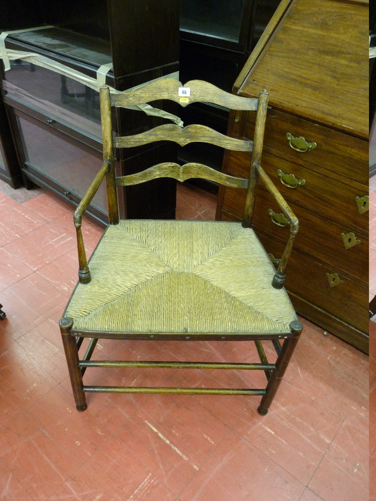 A SIMPLE WIDE RUSH SEATED ELM LADDERBACK ELBOW CHAIR with turned front and side stretchers and