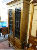 A CIRCA 1900 TALL OAK BOOKCASE with an inverted crown over twin leaded glazed doors and interior