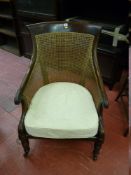 A BERGERE ARMCHAIR, rosewood framed and cane upholstered with scrolled arms and turned front