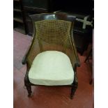 A BERGERE ARMCHAIR, rosewood framed and cane upholstered with scrolled arms and turned front