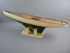 A VINTAGE POND YACHT HULL on stand, clinker built with green and white livery and lead keel (no mast