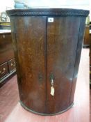 AN ANTIQUE OAK BOW FRONT HANGING WALL CUPBOARD with Greek Key frieze decoration, the twin doors with