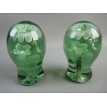 TWO VICTORIAN GREEN GLASS DUMP PAPERWEIGHTS with interior flowers in a vase decoration and rough