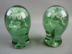 TWO VICTORIAN GREEN GLASS DUMP PAPERWEIGHTS with interior flowers in a vase decoration and rough