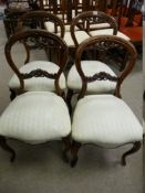 A SET OF FOUR VICTORIAN WALNUT BALLOON BACK SALON CHAIRS with carved top and centre rails, stuff-