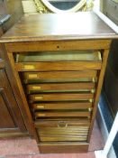 AN OAK TAMBOUR FRONT RISE AND FALL DOCUMENT CABINET with nine interior slide-out trays, 112 x 49.5