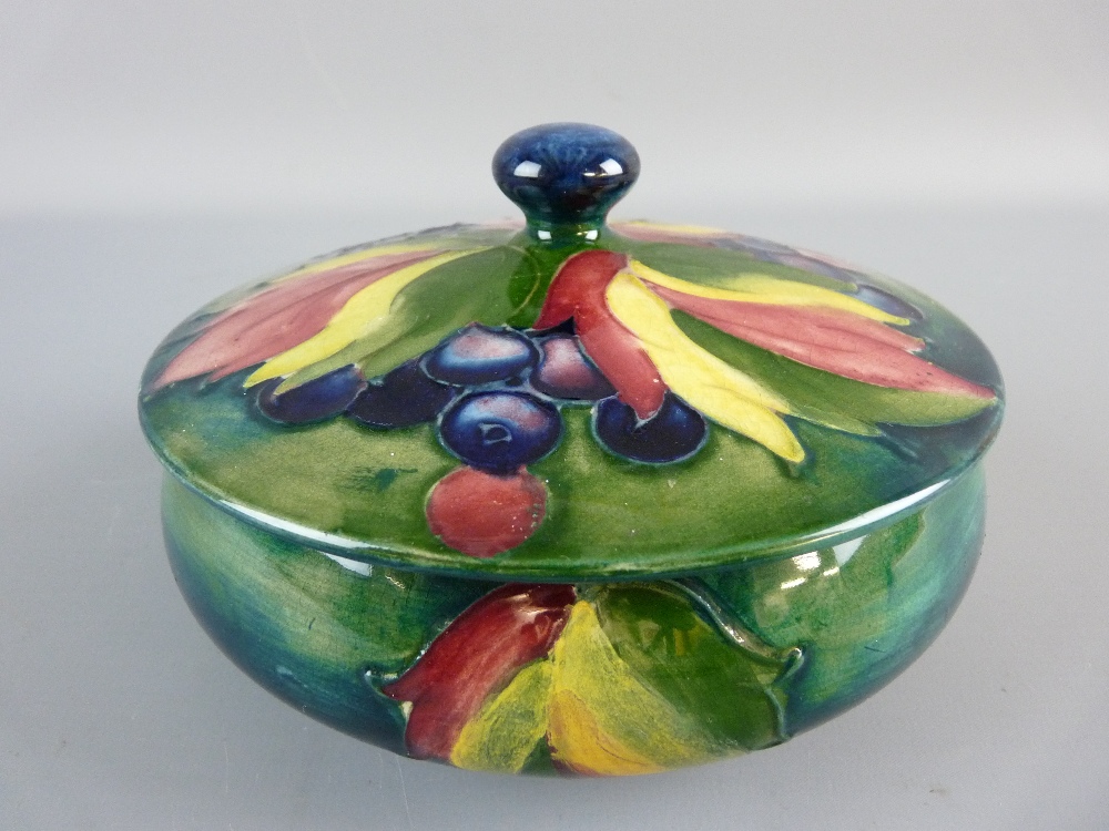 A MOORCROFT LEAF AND BERRY POWDER BOWL AND COVER, 15 cms diameter, on a tonal green/blue ground,