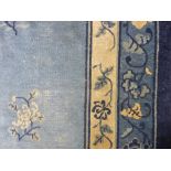 A VINTAGE BLUE GROUND WOOLLEN CARPET with central medallion, scattered floral sprigs and scallop