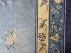 A VINTAGE BLUE GROUND WOOLLEN CARPET with central medallion, scattered floral sprigs and scallop